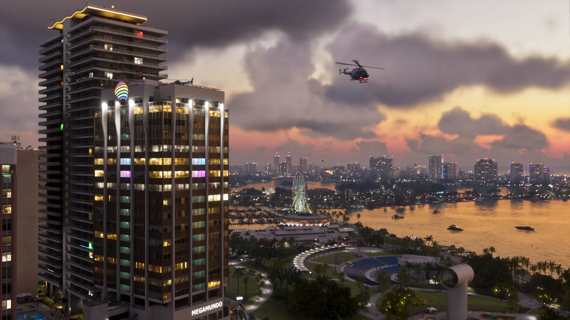 A wide Vice City skyline at golden hour, with illuminated high-rises, a waterfront Ferris wheel, boats on the bay and a helicopter in the sky above.